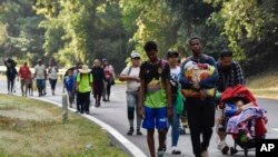 Migrants walk on the side of the highway through Villa Comaltitlan, Chiapas state, southern Mexico, Dec. 27, 2023, as they make their way north to the U.S. border. 