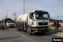 Aid trucks move on a road as Palestinians look on, during a temporary truce between Hamas and Israel, in Rafah, in the southern Gaza Strip, Nov. 25, 2023.