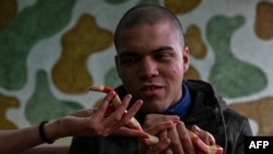 Ahli biologi Beatriz Araujo merawat pasien David de Oliveira Gomes dalam sesi terapi dengan reptil di klinik Walking Equotherapy di Sao Paulo, Brazil, 30 Mei 2023. (ALMEIDA/AFP)