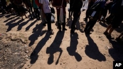 FILE - Migrants wait to be processed by U.S. officials after crossing the Rio Grande and entering the U.S. from Mexico, in Eagle Pass, Texas, Oct. 19, 2023. U.S. President Joe Biden and presidential candidate Donald Trump will visit the U.S./Mexico border soon — but separately.