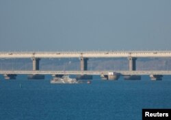 An armed ship sails next to Crimean bridge connecting the Russian mainland with the peninsula across the Kerch Strait, Crimea, July 17, 2023.