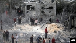 Warga Palestina memeriksa kerusakan rumah yang hancur akibat serangan udara Israel di kota Khan Younis, Jalur Gaza selatan, 22 November 2023. (Foto: AP)