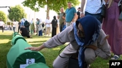 Penyintas dari pembantaian Srebenica 1995 tampak mengelus keranda berisi sisa jasad kerabatnya di pemakaman di Potocari, dekat Srebenica, Bosnia, pada 11 Juli 2024. (Foto: AFP/Elvis Barukcic)