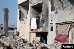 Palestinians stand in a house destroyed by an Israeli strike, amid the ongoing conflict between Israel and the Palestinian Islamist group Hamas, in Rafah, southern Gaza Strip, Jan. 1, 2024.