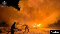 អ្នកពន្លត់អគ្គិភ័យប្រតិបត្តិការពន្លត់ភ្លើងឆេះដោយសារការវាយប្រហារដោយដ្រូននៅកំពង់ផែមួយ ក្នុងតំបន់ Odesa ប្រទេសអ៊ុយក្រែន ថ្ងៃទី២៦ ខែកញ្ញា ឆ្នាំ ២០២៣។ (State Emergency Service of Ukraine, via Reuters)