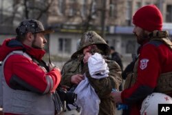 A wounded resident talks with paramedics after Russia's missile attack in Kyiv, Ukraine, Dec. 29, 2023.
