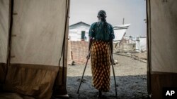 The 42-year-old mother of four who was raped in the Bulengo displacement camp where she had fled war in eastern Congo stands in a doorway at the camp, Aug. 23, 2023. 