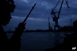 A Ukraine Special Operations Forces officer talks on the radio while navigating the Dnipro River during a night mission near Kherson, Ukraine, on June 11, 2023.