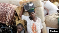 Mwanamke mkimbizi akiwa amebeba redio akiwa kwenye ufukwe wa ziwa Tanganyika Picha na REUTERS/Thomas Mukoya