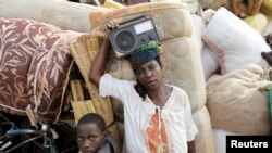 Mwanamke mkimbizi akiwa amebeba redio akiwa kwenye ufukwe wa ziwa Tanganyika Picha na REUTERS/Thomas Mukoya