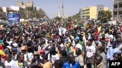 FILE - Civil society groups and political groups hold placards as they march calling on authorities respect the election date, in Dakar, on Feb. 17, 2024.
