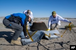 In this NASA photo, members of a recovery team from Lockheed Martin prepare to transport the asteroid sample, which touched down at the Department of Defense's Utah Test and Training Range on Sunday, Sept. 24, 2023. (Keegan Barber/NASA via AP)