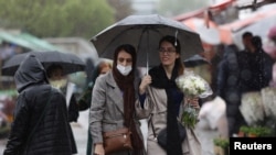 FILE - Iranian women walk through rain in a flower market, ahead of Nowruz, the Iranian New Year, in Tehran, Iran March 16, 2023.