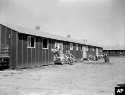 FILE - Relocated Japanese Americans sit on small front porches at barracks at Rohwer Relocation Center near Rohwer, Arkansas, Sept. 21, 1942.