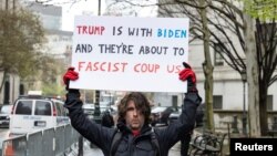 مکسوِل ازاریلو روز پنجشنبه با شعاری در مقابل محکمه حاضر شد که در آن نوشته که ترمپ با بایدن است و آنها در حال یک کودتای فاشیستی هستند.