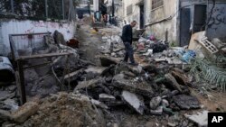 Warga Palestina berjalan pasca serangan militer Israel di kamp pengungsi Nur Shams di Tepi Barat, 27 Desember 2023. (Foto: AP)