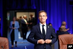 Perdana Menteri Swedia Ulf Kristersson mengancingkan jaketnya saat ia tiba untuk pertemuan meja bundar Dewan Atlantik Utara selama KTT NATO di Vilnius, Lithuania, Selasa, 11 Juli 2023. (AP/Mindaugas Kulbis)