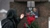 A woman touches a photo of Alexey Navalny after laying flowers at the Memorial to Victims of Political Repression in St. Petersburg, Russia, on Feb. 17, 2024.