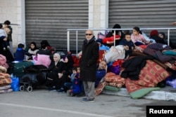 Palestinians rest next to their belongings, as they flee their houses, after they were ordered by the Israeli army to evacuate the area, in Bureij in the central Gaza Strip, Dec. 26, 2023.