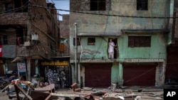 FILE - A Muslim man watches from his house after a shop was demolished in the area that saw communal violence during a Hindu religious procession in New Delhi's northwest Jahangirpuri neighborhood, in New Delhi, India, April 20, 2022.