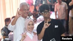 Capres Ganjar Pranowo bersama istrinya Siti Atikoh dan anaknya Alam Ganjar menunjukkan jari yang telah diberi tinta setelah mencoblos di salah satu TPS di Semarang, Jawa Tengah, pada 14 Februari 2024. (Foto: Antara Foto/Akbar Nugroho Gumay via Reuters)
