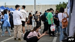 FILE - China's slowing economy has left millions of young people competing for an ever-slimming raft of jobs and facing an increasingly uncertain future. In this photo taken Aug. 26, 2022, a woman uses her phone during a job fair in Beijing. 