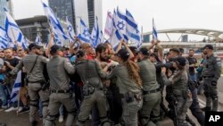 اسرائیلی پولیس 23 مارچ 2023 کو اسرائیل میں عدالتی نظام کو تبدیل کرنے کے وزیر اعظم بنجمن نیتن یاہو کی حکومت کے منصوبوں کے خلاف تل ابیب میں احتجاج کے دوران ایک سڑک بلاک کرنے والے مظاہرین کے ساتھ ہاتھا پائی کر رہی ہے۔