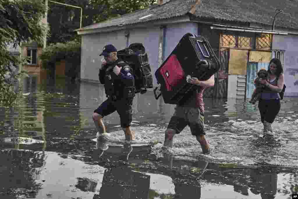 Local residents carry their belongs as they evacuated from a flooded neighborhood in Kherson, Ukraine, June 6, 2023.