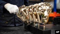 FILE - A foundry man places a completed British Academy Film Awards mask amongst others as part of the process to create BAFTA masks at FSE Foundry in Braintree, Essex, on Jan. 24, 2024. 