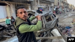 A man gestures in front of the car in which three sons of Hamas leader Ismail Haniyeh were reportedly killed in an Israeli airstrike in al-Shati camp, west of Gaza City on April 10, 2024.