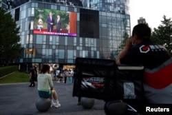 A giant screen shows news footage of U.S. Special Presidential Envoy for Climate John Kerry shaking hands with Chinese Vice Premier Han Zheng before a meeting, in Beijing, China, July 19, 2023.