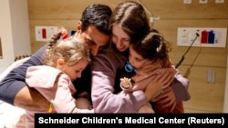 Aviv Asher, Raz Asher, and their mother Doron Asher meet with Yoni Asher, Raz and Aviv's father and Doron's husband, after returning to Israel at the Schneider Children's Medical Center, in Petah Tikva, Israel, in this handout picture released Nov. 25, 2023.