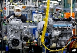 FILE - A Nissan Motor Co. factory worker checks an engine on an assembly line at its plant in Yokohama, Japan, near Tokyo, Aug. 2, 2017.