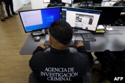 Seorang agen Badan Investigasi Kriminal di Mexico City, tengah memeriksa berkas melalui komputer di kantorya, 7 Maret 2023. (CLAUDIO CRUZ/AFP)
