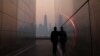 A man stands in the Empty Sky 911 Memorial in Jersey City, N.J., looking toward the One World Trade Center tower in New York City shortly after sunrise as haze and smoke caused by wildfires in Canada hangs over the Manhattan skyline, June 8, 2023. 