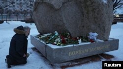 A man kneels at the monument to the victims of political repressions, where people lay flowers following the death of Russian opposition leader Alexey Navalny, in Saint Petersburg, Russia, Feb. 16, 2024.