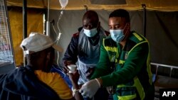 FILE - A dehydrated patient is given water as he receives treatment at a field hospital in Kanana, Hammanskraal, South Africa, May 31, 2023. 