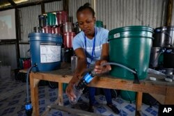 Hellen Simichi, a member of the Bucket Ministry, a Christian nonprofit organization, demonstrates how to use a bucket filter to locals in Athi River, Machakos county, Kenya, Oct. 17, 2023.
