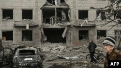 Warga berjalan di depan gedung yang hancur akibat serangan Rusia di Sloviansk, Ukraina pada 27 Maret 2023. (Foto: AFP)