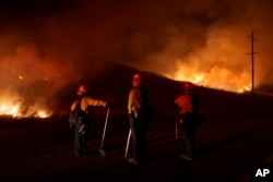 FILE - Firefighters monitor as flames consume brush along Gilman Springs Road during the Rabbit Fire, July 14, 2023, in Moreno Valley, California.