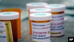 FILE - Fake pill bottles with messages about Purdue Pharma are displayed during a protest outside the courthouse where the company's bankruptcy proceedings were taking place, in White Plains, New York, Aug. 9, 2021. 