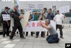 Protesters portraying former Taiwanese President Ma Ying-jeou, right, and Chinese President Xi Jinping, second left, perform as Ma leaves for China, outside Taoyuan International Airport in Taoyuan City, Taiwan, April 1, 2024.