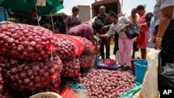 People buy onions at an open market in Nairobi, Kenya Tuesday, Sept. 12, 2023. (AP Photo/Brian Inganga)