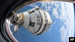 This photo provided by NASA shows Boeing's Starliner spacecraft docked to the Harmony module's forward port on July 3, 2024, seen from a window on the SpaceX Dragon Endeavour spacecraft docked to the adjacent port. 