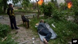 A man lies on the ground as he watches his burning home, destroyed by a Russian airstrike in Vovchansk, Ukraine, May 11, 2024.