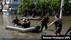 A woman is evacuated from a flooded neighborhood in Kherson, Ukraine, Wednesday, June 7, 2023. (AP Photo/Roman Hrytsyna)