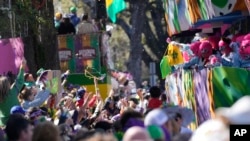 Orang-orang berebut manik-manik yang dibagikan saat parade Krewe of Iris Mardi Gras di New Orleans, 18 Februari 2023. (AP/Gerald Herbert)