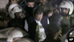Police officers make way for former prime minister Imran Khan, center, upon his arrival at court, in Lahore, Pakistan, March 17, 2023. 