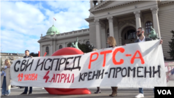 Aktivisti Kreni promeni drže transparent kojim se poziva na protesni skup ispred RTS-a 4, aprila, zbog ponašanja države u vezi sa kompanijom Rio tinto i eventualnim iskopavanjem litijuma, ispred figure crvenog puža, u Beogradu, 2. aprila 2024. (Foto: Glas Amerike/Rade Ranković)
