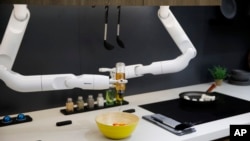 Bot Chef menuangkan saus ke dalam salad selama demonstrasi di samping kompor listrik yang dipajang di stan Samsung selama pameran teknologi CES di Las Vegas. (Foto: AP)